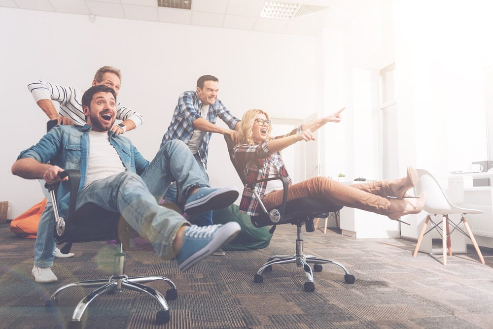 offie workers playing on desk chairs