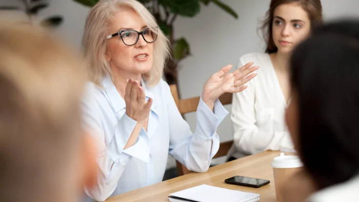 A group of women sitting at a table and talking to each other.