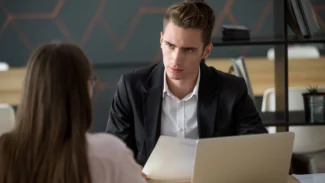 A man and woman in an office talking to each other.