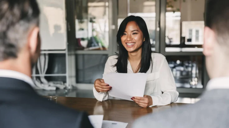 A woman is sitting at a table with a paper in front of her.