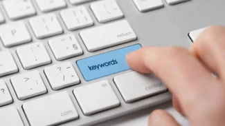 A person typing the word keywords on a keyboard.