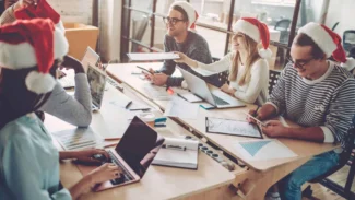 A group of people in santa hats working at a desk.