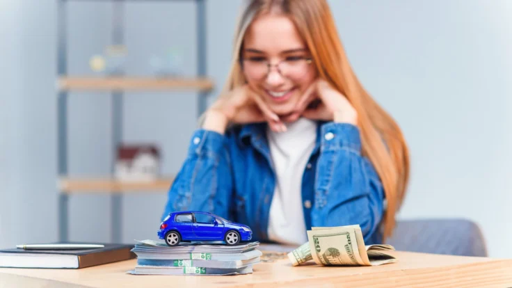 A woman sitting at a table with a blue car and money.