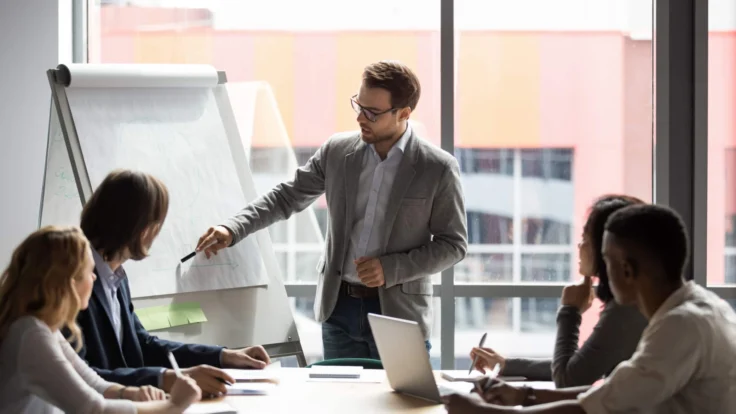 A businessman giving a presentation to a group of people in a meeting room.