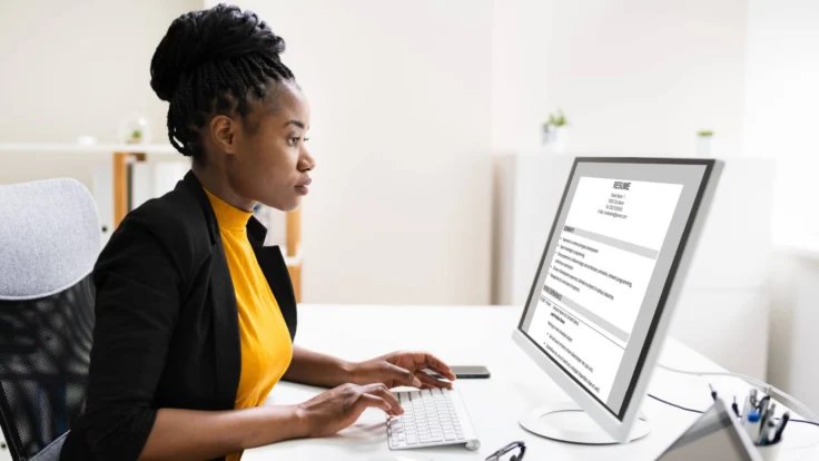 A woman is working on her resume on a computer.