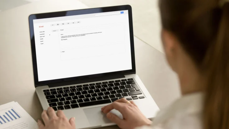 A woman is using a laptop to send an email.