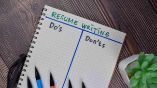 A notebook with the words resume writing and pens next to it.