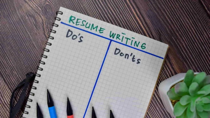 A notebook with the words resume writing and pens next to it.