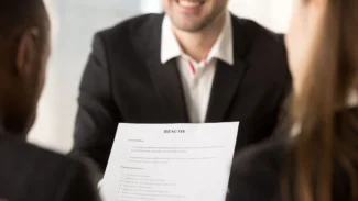 A man in a suit is looking at a resume.