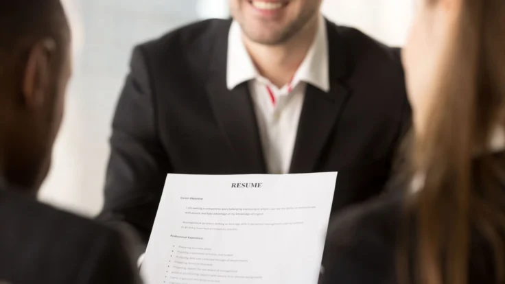 A man in a suit is looking at a resume.