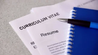 A blue pen sits on top of a paper with a curriculum vitae.