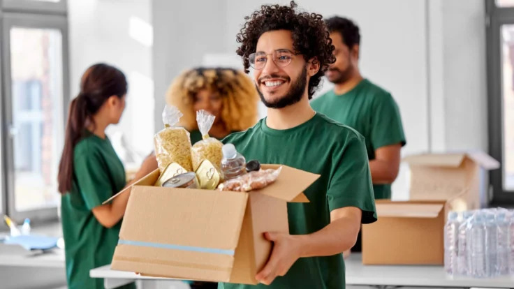 A man holding a box of food in front of a group of people.