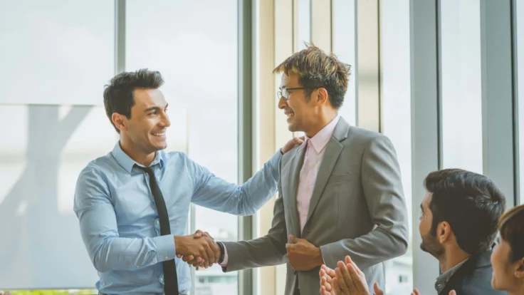 Two businessmen shaking hands in an office.