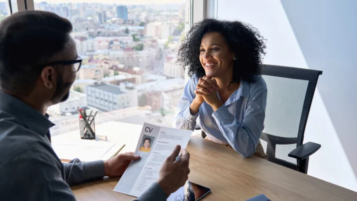 A man and woman talking at a desk in an office.