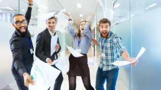 A group of business people are throwing papers in an office.