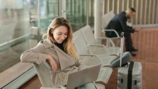 A woman sitting in an airport with a laptop.