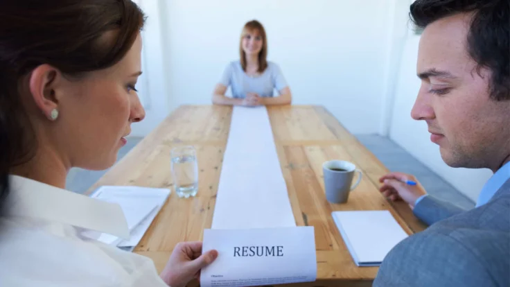 A man and woman sitting at a table with a resume in front of them.