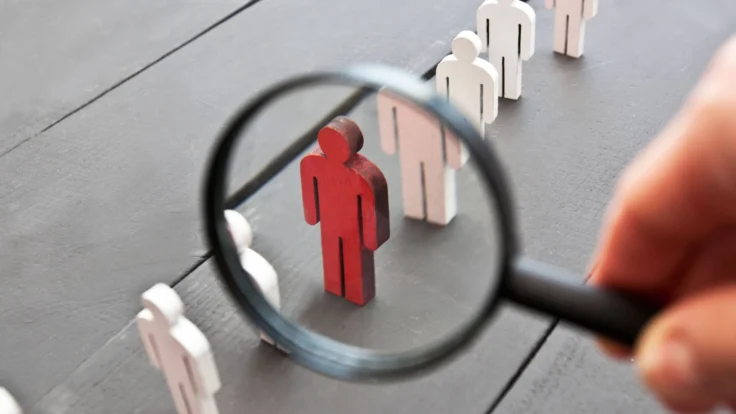 A person looking through a magnifying glass at a group of people.