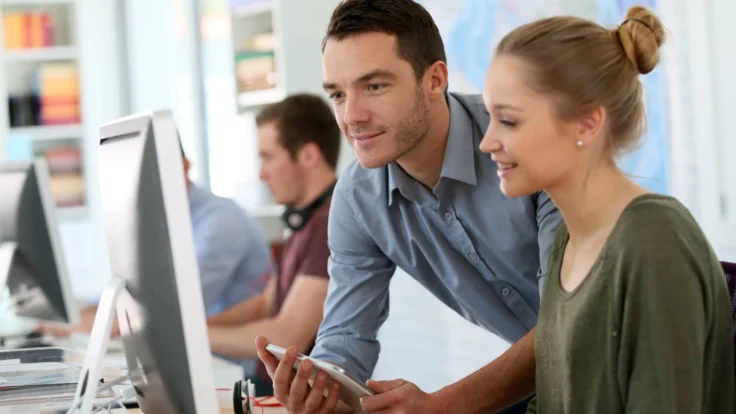 A man and woman looking at a computer screen.