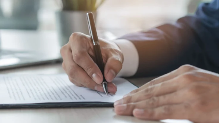 A businessman signing a contract with a pen.