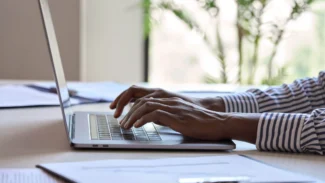 A man typing on a laptop computer.