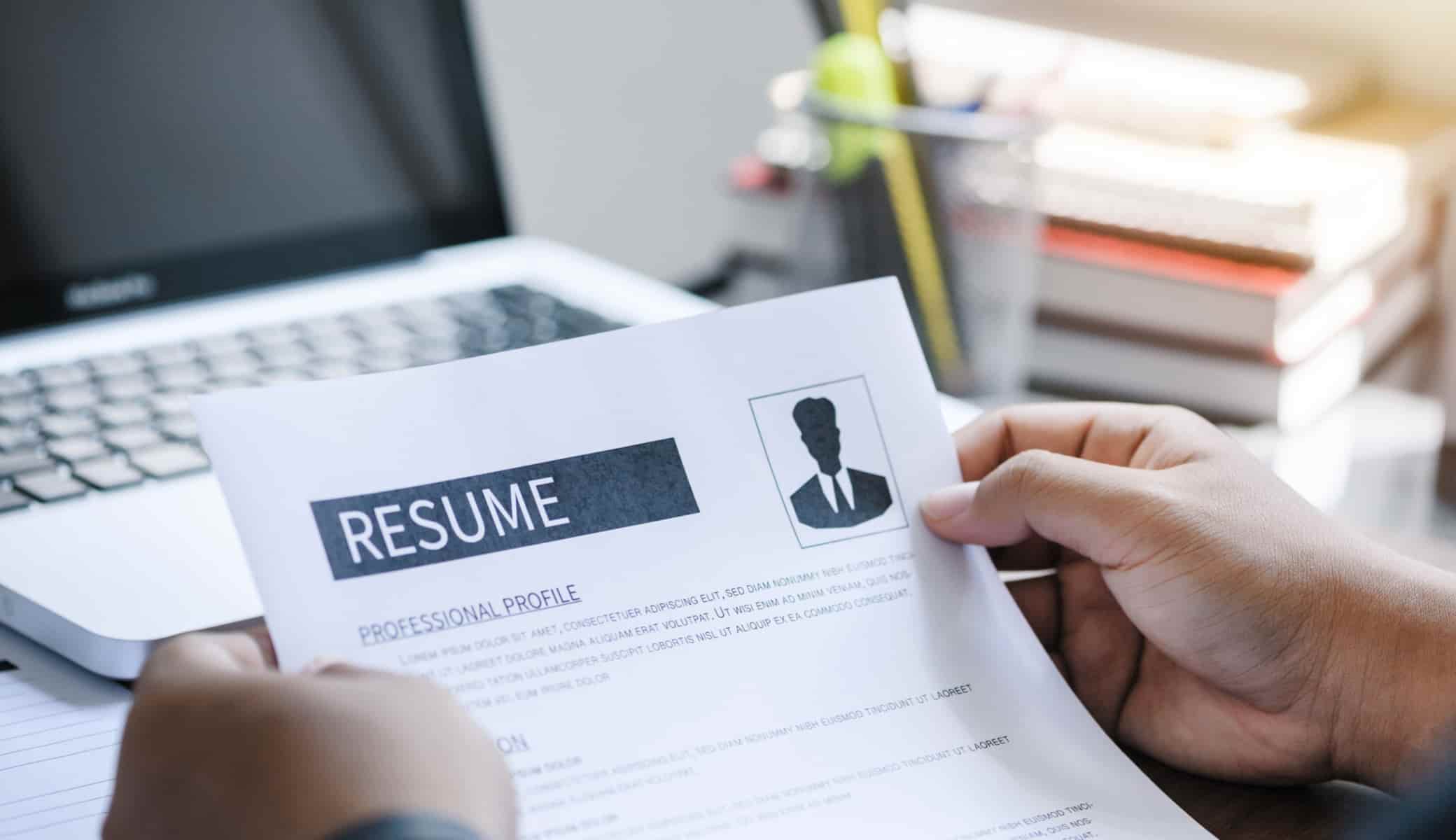 Job Resume Document Out From Laptop. Hands Holding Cv Resume Pap