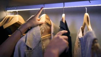 A person is putting clothes on a hanger in a closet.